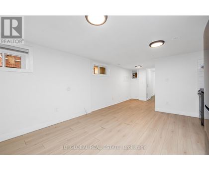 A spacious room with wooden flooring and white walls.