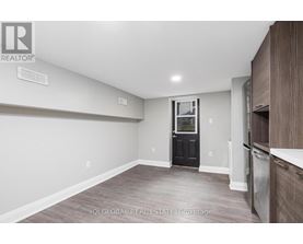 A room with a black door and wooden flooring.