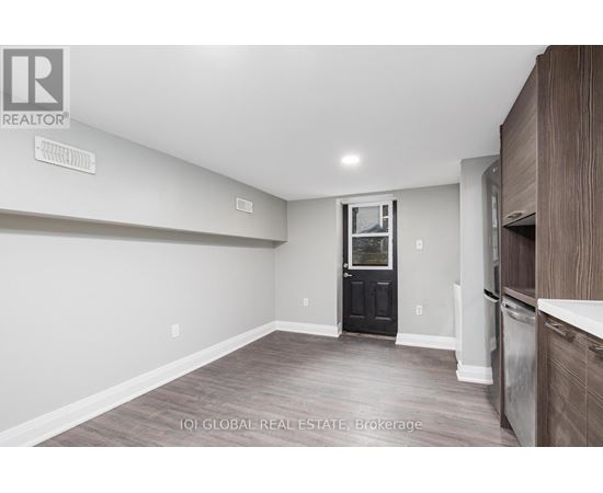 A room with a black door and wooden flooring.