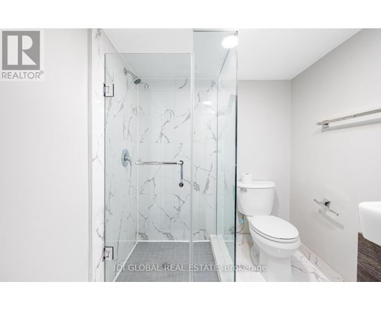 A white toilet is in a bathroom with a glass shower door.