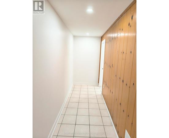 A long hallway with white tile floors and wood paneling on the walls.