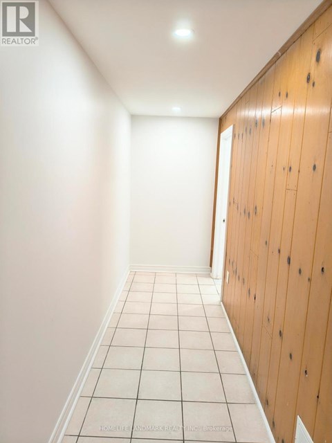 A long hallway with white tile floors and wood paneling on the walls.