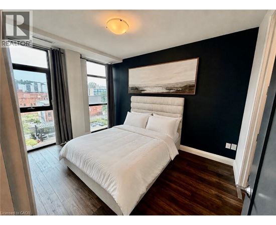 A bedroom with a large bed and a window overlooking a cityscape.