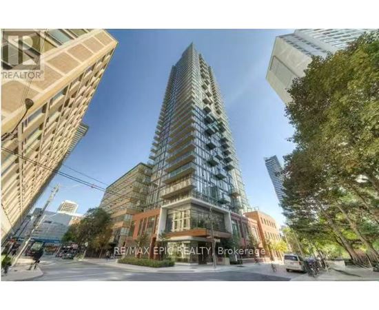 A tall, modern glass building stands in the middle of a city street.