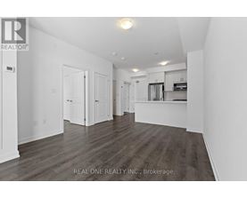 A spacious room with wooden flooring and white walls.