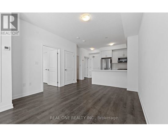 A spacious room with wooden flooring and white walls.