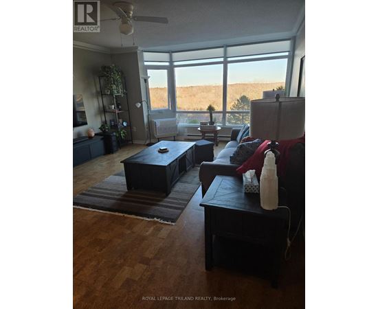 A living room with a couch, ottoman, and a fan.