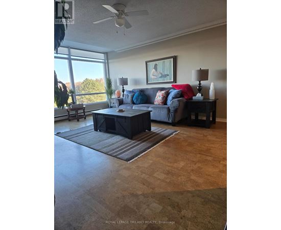 A living room with a couch, a coffee table, and a ceiling fan.