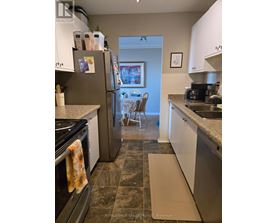 A kitchen with a refrigerator, oven, and sink.