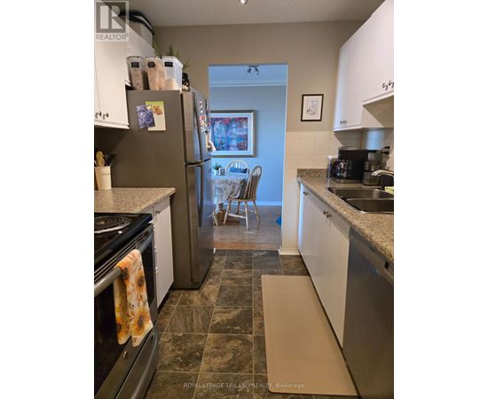 A kitchen with a refrigerator, oven, and sink.
