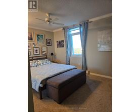 A bedroom with a bed, a ceiling fan, and pictures on the wall.