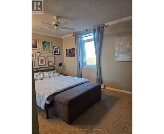 A bedroom with a bed, a ceiling fan, and pictures on the wall.