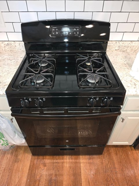 A black stove top oven with four burners and a digital display is in a kitchen.