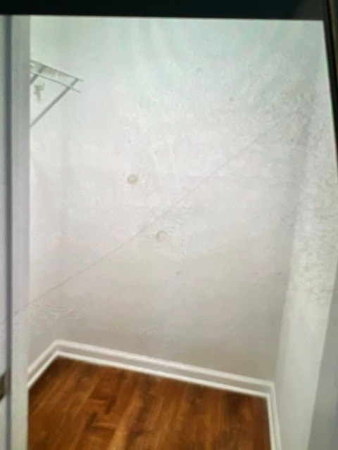 A white wall with a wooden floor and a white door.