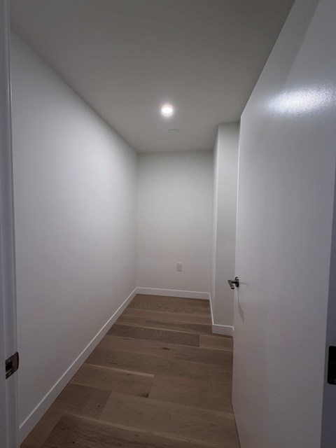 A hallway with wooden floors and white walls.