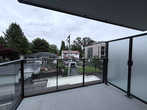 A balcony with a glass railing overlooks a residential area.