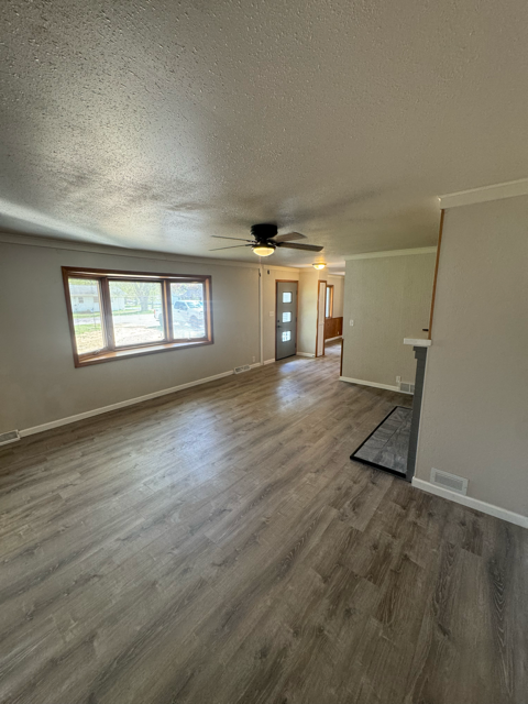 A room with a ceiling fan and wooden flooring.
