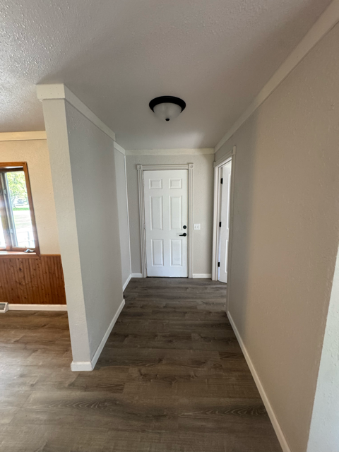 A long, narrow hallway with a white door at the end.