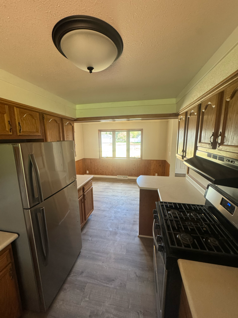 A kitchen with a stainless steel refrigerator and black stove top oven.