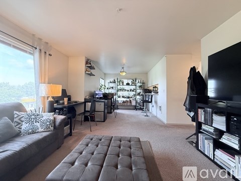 A living room with a grey couch and a black ottoman.