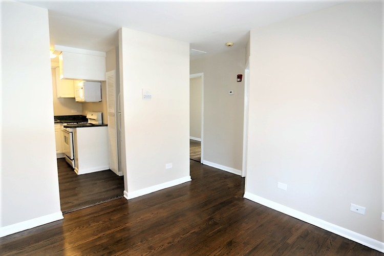 A kitchen with white cabinets and a stove top oven is visible through an open door.