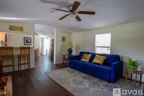 A living room with a blue couch and a ceiling fan.