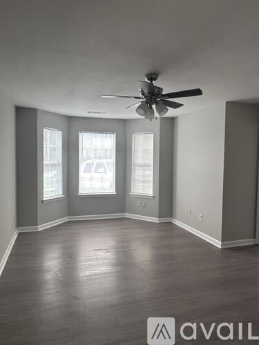 A room with a ceiling fan and three windows.