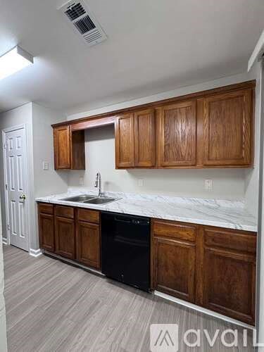 A kitchen with wooden cabinets and a black dishwasher.