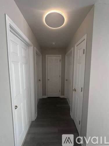 A hallway with white doors and a circular light on the ceiling.