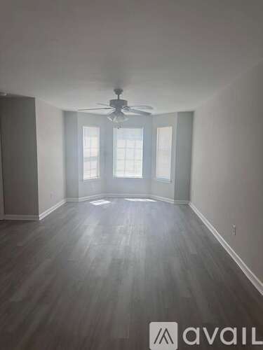 A room with a ceiling fan and wooden flooring.