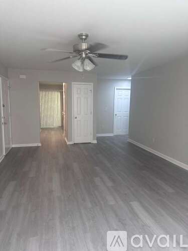 A room with a ceiling fan and light, and a wooden floor.