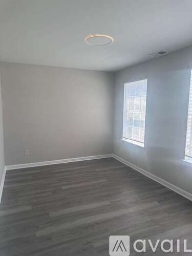 A room with wooden flooring and a window with blinds.