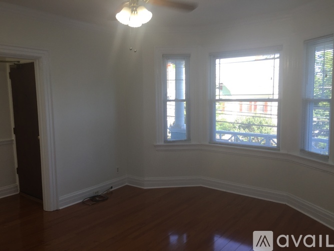 A room with a wooden floor and a window overlooking a green lawn.