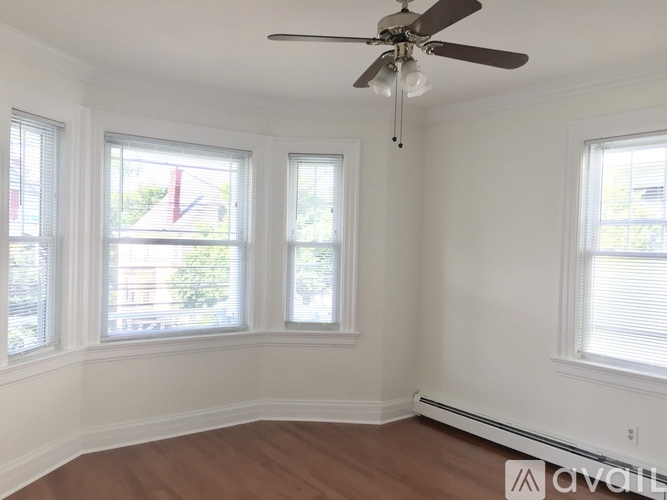 A room with a ceiling fan and three windows.