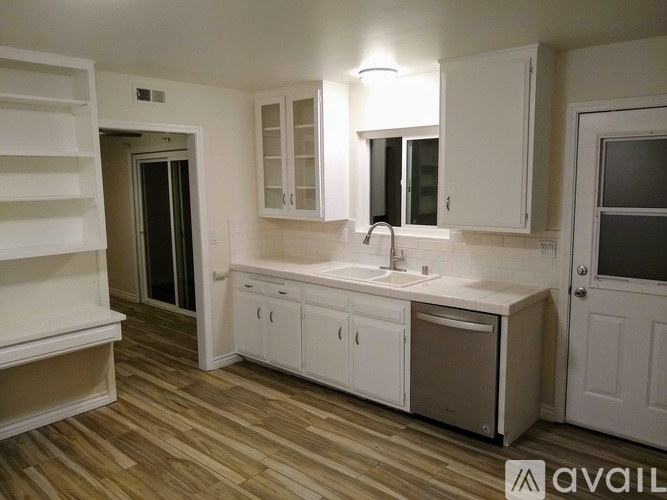 A kitchen with white cabinets and a wooden floor.