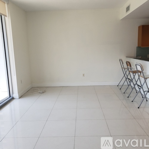 A room with white tile flooring and a row of folding chairs.