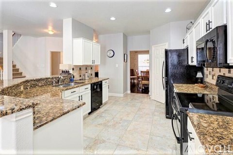 A kitchen with granite countertops and white cabinets.