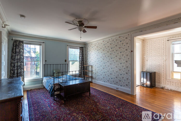 A bedroom with a bed, a rug, and a ceiling fan.