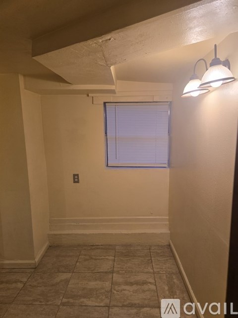 A room with a window and a light on the wall.