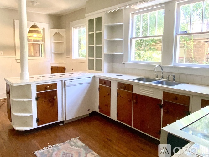 A kitchen with white cabinets and a wooden floor.