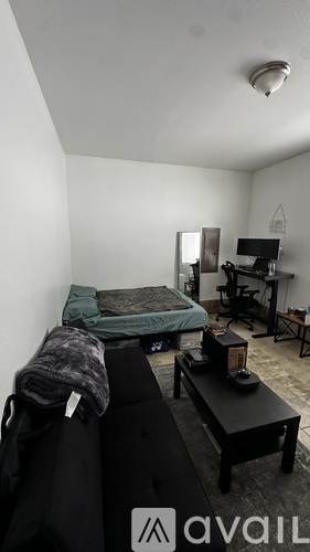 A bedroom with a bed, a desk, and a chair.
