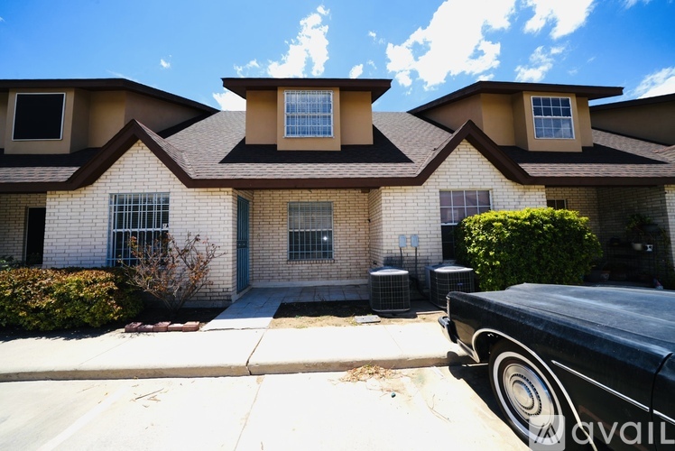 A black car is parked in front of a house with a white and brown facade.