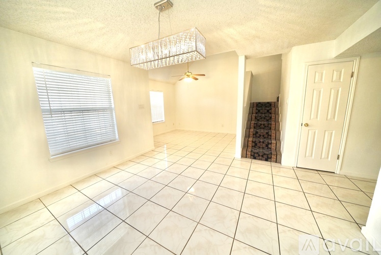 A room with white tiled flooring and a chandelier hanging from the ceiling.