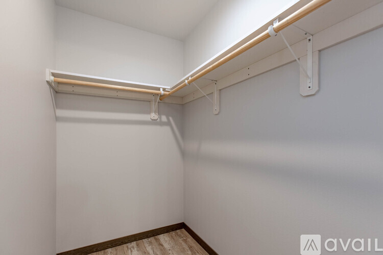 A white wall with a wooden floor and a white pipe running along the wall.