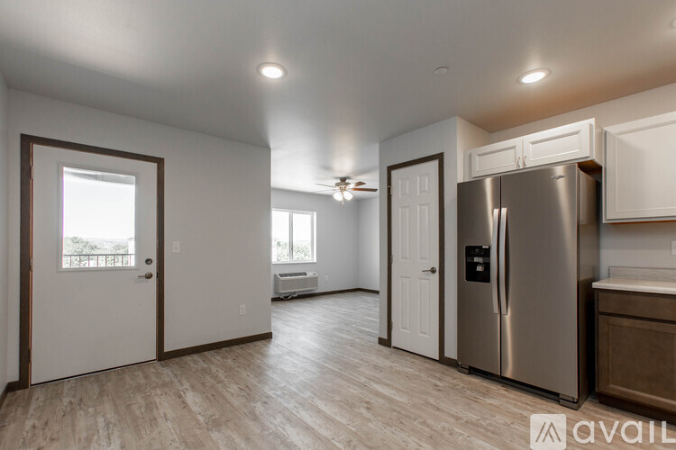 A kitchen with a stainless steel refrigerator and wooden flooring.