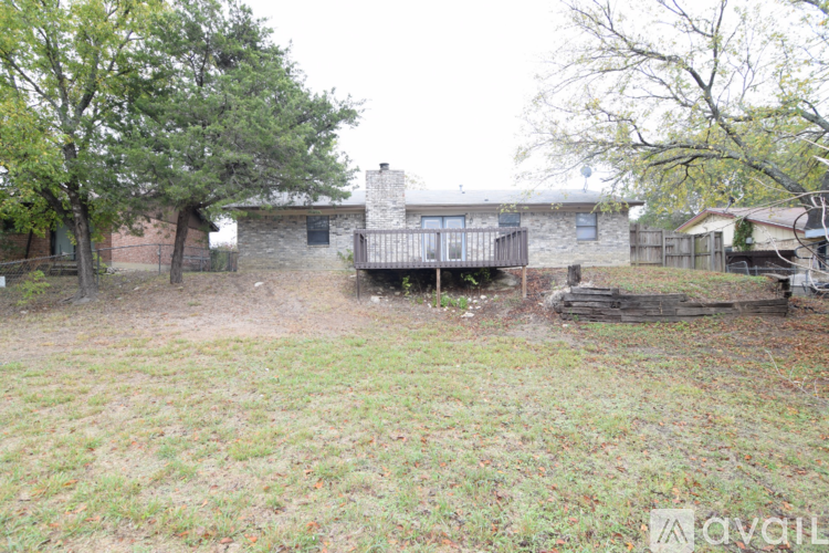 A grassy area with a house and a deck in the background.