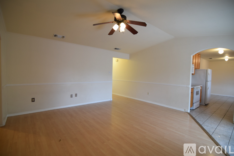 A spacious room with a ceiling fan and wooden flooring.