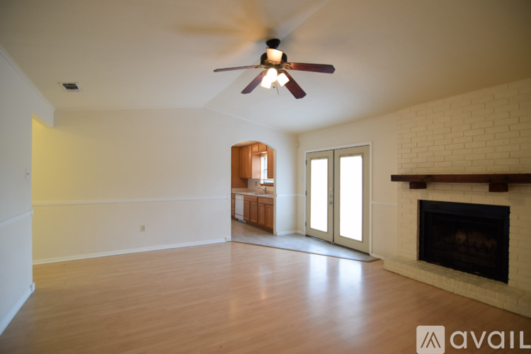 A spacious living room with a fireplace and a ceiling fan.