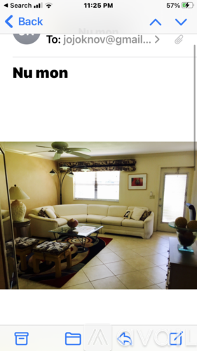 A living room with a white sofa and a fan on the ceiling.
