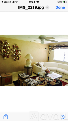 A room with a white couch, a table with a lamp, and a wall decoration.